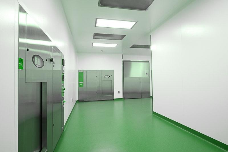 Cleanroom corridor with a seamless green epoxy floor and stainless-steel pass-through doors